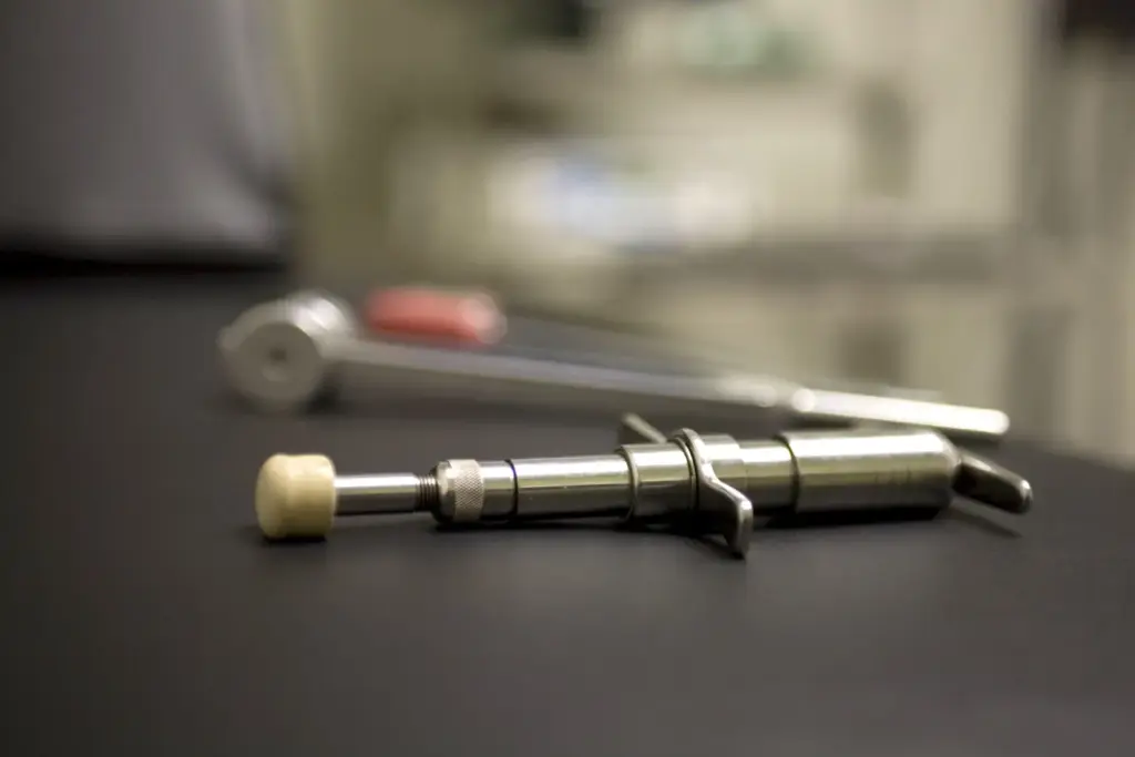 An Activator adjusting instrument: a small spring-loaded hand-held tool with a rubber tip, lying on a table.