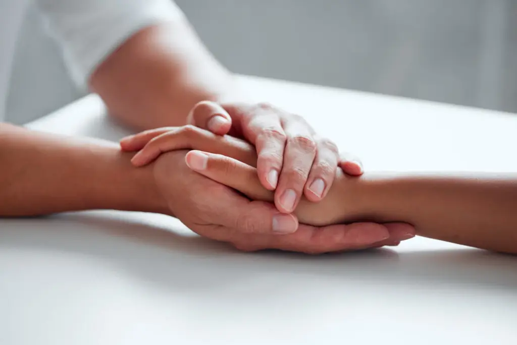 One hand gently holding another hand’s wrist.