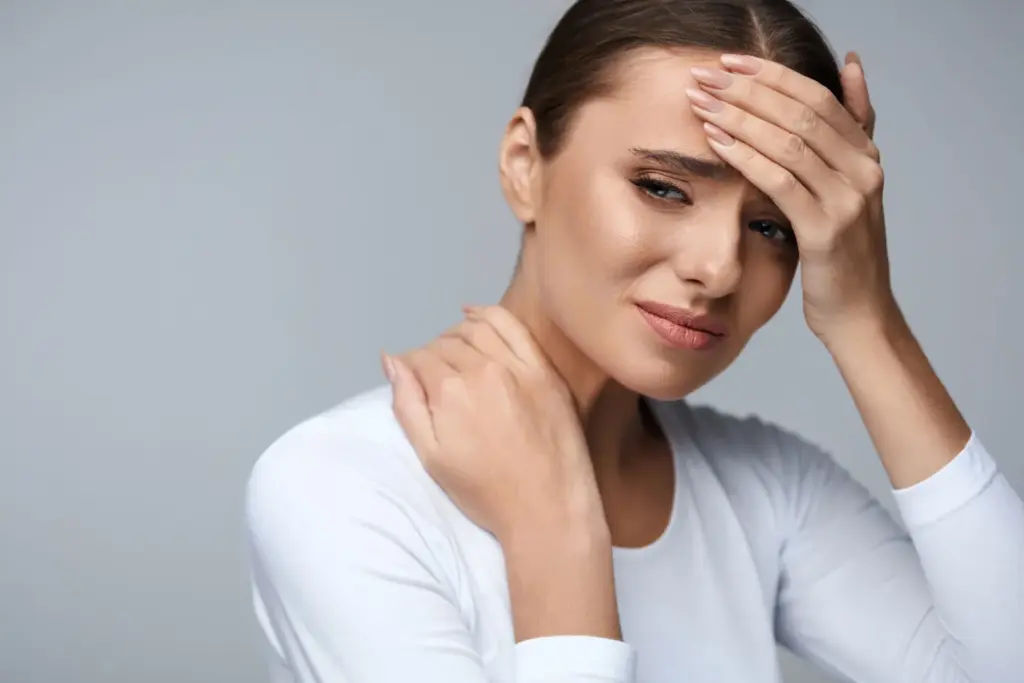 A woman with a headache holding her forehead and the back of her neck.